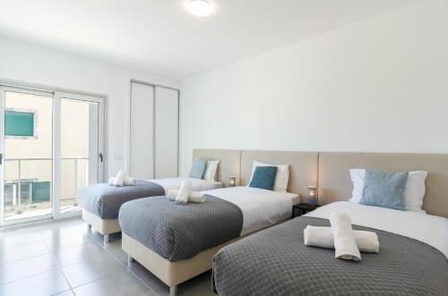 drie bedden in een kamer met een groot raam bij Terraços Do Mar - Rooftop Pool with Sea View in Nazaré