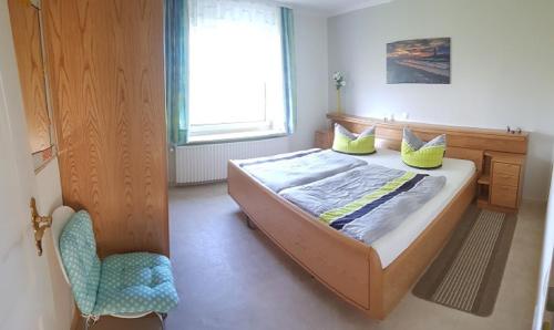 a bedroom with a bed with a chair and a window at Haus Christine in Wremen