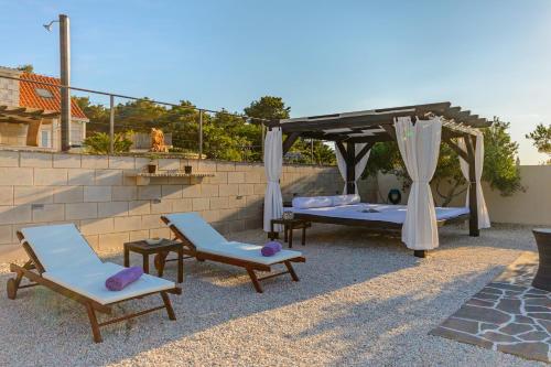 a patio with chairs and a bed and a canopy at Villa Mis in Supetar