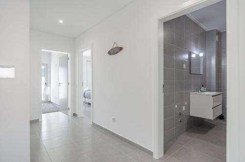 een witte badkamer met een wastafel en een spiegel bij Terraços Do Mar - Rooftop Pool with Sea View in Nazaré