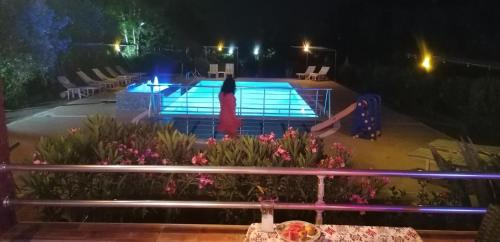 a woman standing in front of a swimming pool at night at Hotel Grün in Kızılot