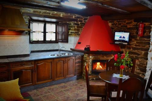cocina con chimenea, mesa y fogones en Casa Freixe Apartamentos Rurales, en Santa Eulalia de Oscos