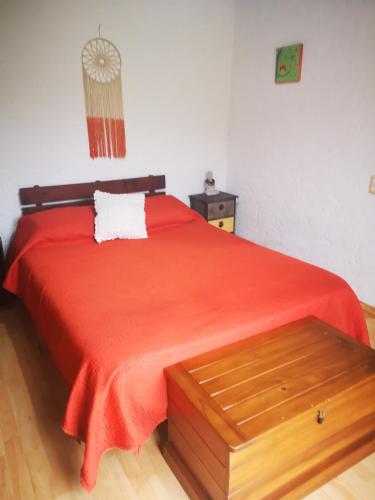 a bedroom with a bed with a red bedspread at Adorable microcasa a 4km del centro de Maldonado y de playa mansa, en barrio muy tranquilo! in Maldonado
