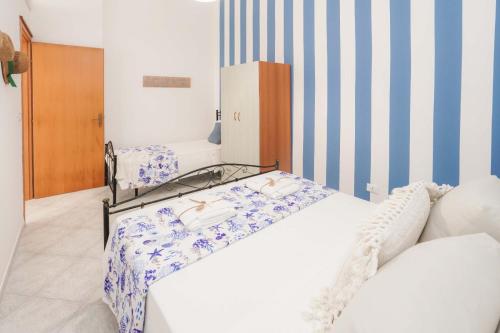 2 łóżka w pokoju z niebiesko-białymi paskami w obiekcie Poésia w mieście San Foca