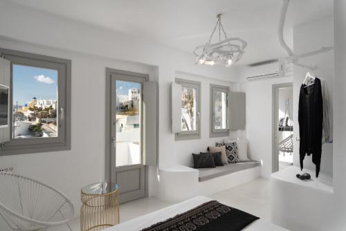 a white room with a chandelier and a bathroom at Canyon Santorini in Fira