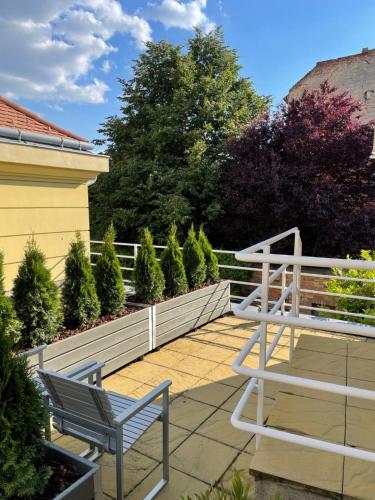 a patio with two benches and a fence and trees at STM3 Apartman in Pécs