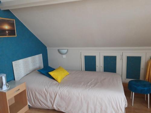 a bedroom with a bed with a yellow pillow at Les Puits Bessin Normandie in Sommervieu