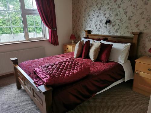 1 dormitorio con 1 cama grande con mantas y almohadas rojas en Noraville House en Killarney