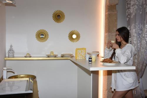 ポリニャーノ・ア・マーレにあるGold White Exclusive Houseの食器を持ってカウンターに立つ女