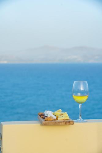 a glass of wine and a plate of food and cheese at Astoria Hotel in Agia Galini