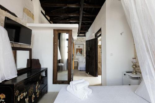een slaapkamer met witte muren en een grote spiegel bij Antonia's House - Old town in Rethimnon
