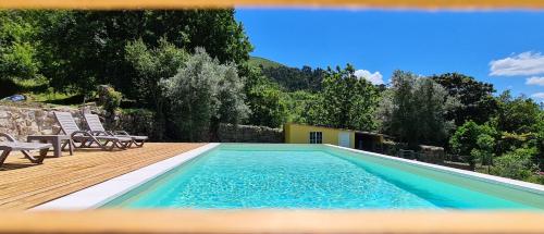 a swimming pool with chairs on a wooden deck at casa de ramalhinha in Caldelas