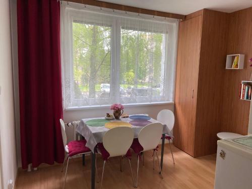 een eettafel met stoelen en een raam bij Apartment Fialka in Olomouc