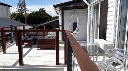 a balcony with a bench and a chair on a house at Maple Villa - The Beach House by the bay in Brisbane