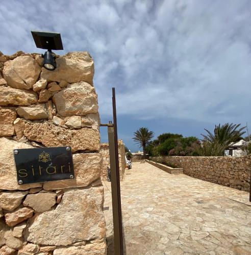 a sign on the side of a stone wall at Sitari Villa Lampedusa in Lampedusa