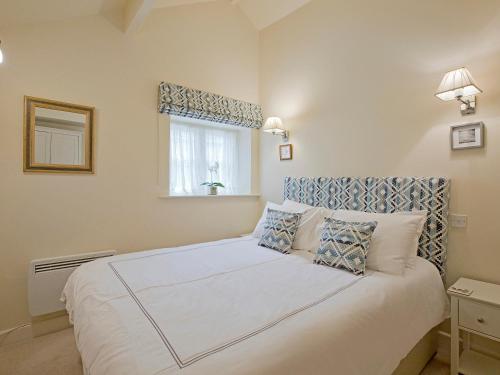 a bedroom with a large white bed with a window at Reynard Ing Cottage in Addingham