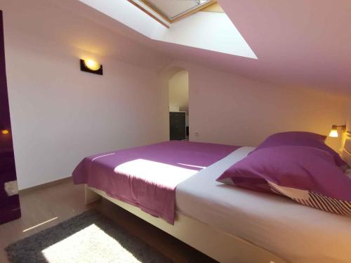 a bedroom with a large bed with purple sheets at Apartment in Crikvenica 5739 in Dramalj