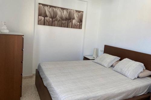 1 dormitorio con 1 cama y una pintura en la pared en Vivienda adosada a 150m de la playa + patio + wifi, en Tarifa