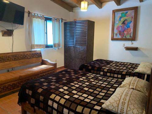 a room with two beds and a couch and a television at Betos Departamentos in Valle de Bravo