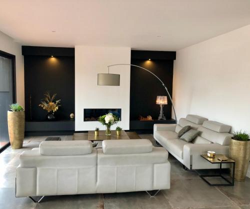 a living room with two white couches and a fireplace at HÔTELYA - Lille Villeneuve d'Ascq in Villeneuve d'Ascq