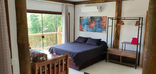 um quarto com uma cama e uma grande janela em Siriúba Reserve em Ilhabela