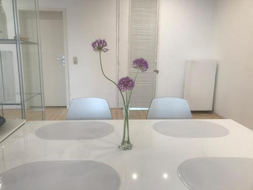 a vase with purple flowers on a table with two chairs at Gästehaus pack of patches in Jena