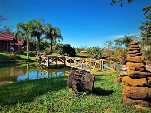 un puente de madera sobre un río con una pared de piedra en Pousada Village dos Canyons, en Praia Grande
