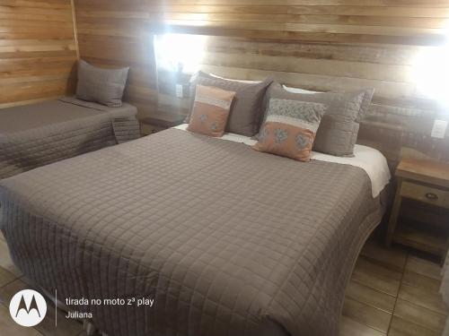 two beds in a room with wooden walls at Pousada Vila dos Butias in Urubici