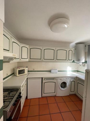 a kitchen with white cabinets and a washing machine at Marina arcadas in Vilamoura