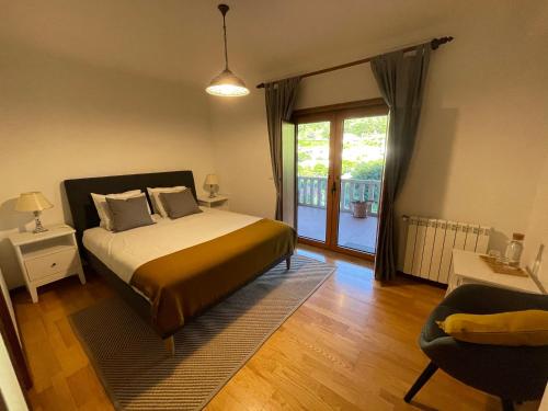 een slaapkamer met een bed en een glazen schuifdeur bij Casa do Pedrógo in Geres