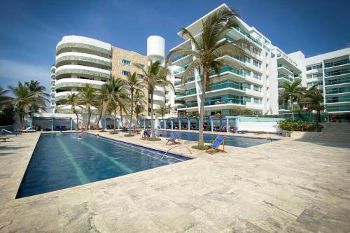 a swimming pool in front of a building with palm trees at Apartamento Cartagena en Morros frente a la playa in Cartagena de Indias