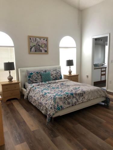 a bedroom with a bed and two lamps and two windows at Pool Home 15 Minutes From Disney in Davenport