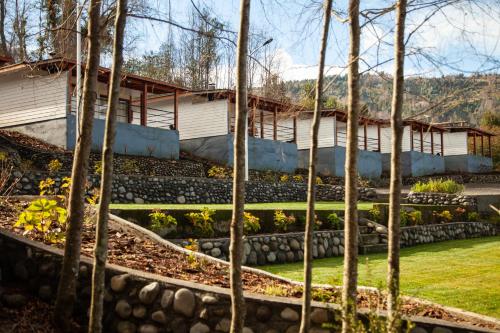 a house with a garden with trees in the foreground at Cabañas Lomas de Ensenada in Licán Ray