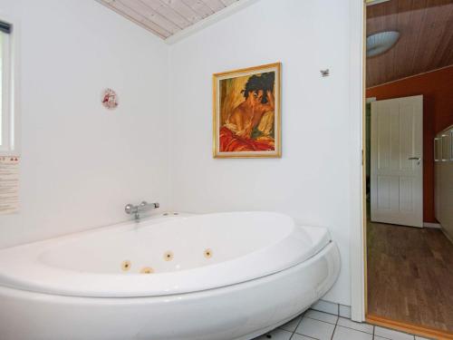 La salle de bains est pourvue d'une baignoire blanche et d'une peinture murale. dans l'établissement 6 person holiday home in Glesborg, à Fjellerup Strand