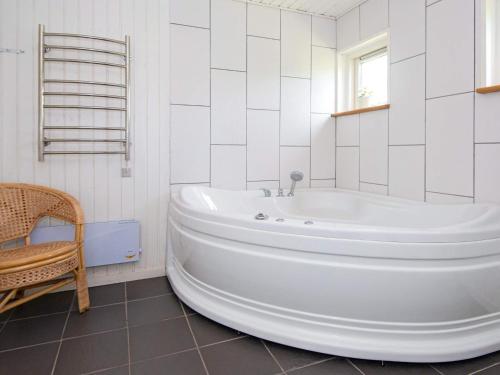 een witte badkamer met een bad en een stoel bij 8 person holiday home in rsted in Ørsted