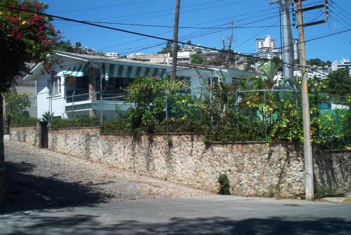a stone wall with plants on it next to a street at Casa del trébol in Acapulco