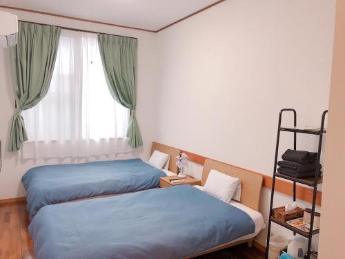 2 Betten in einem Zimmer mit Fenster in der Unterkunft Joya in Ishigaki-jima