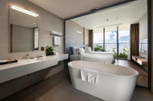 Flamingos Cat Ba Resort luxury في هاي فونج: حمام مع حوض كبير وسرير وحوض استحمام