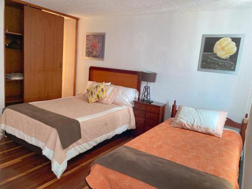 a bedroom with two beds and a dresser with a lamp at Bed and Breakfast La Uvilla in Quito