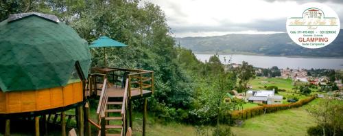 a tree house with a ladder next to a lake at Glamping sede campestre Mirador de Pueblo Viejo in Guatavita