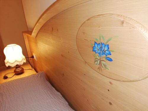 a bedroom with a wooden headboard with a blue flower on it at CAMERE LARICE in Auronzo di Cadore