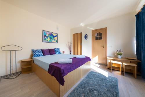 een slaapkamer met een groot bed met paarse lakens bij Vila Adriana in Eforie Nord