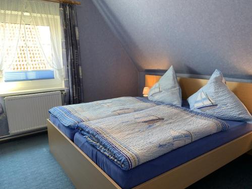 a bedroom with a bed with blue sheets and a window at Horizont in Grube