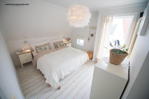 Habitación blanca con cama y lámpara de araña. en Kalvåg Holidayapartment, en Kalvåg