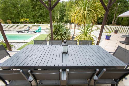 - une table de pique-nique noire avec des chaises et une piscine dans l'établissement La Villa Minvia les Landes entre mer et montagne, à Saint-Vincent-de-Paul