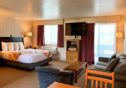 a hotel room with a bed and a living room at Coachman Inn Oak Harbor in Oak Harbor
