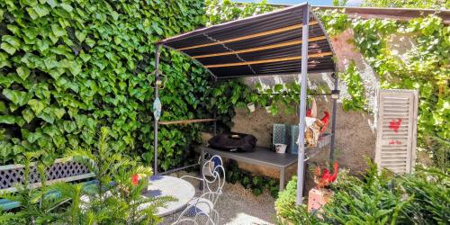 a garden with a table and a bench and a hedge at GITE LE COQ ROUGE in Eguisheim