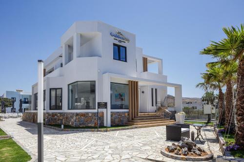 a white house with palm trees in front of it at Golden Bay Boutique Hotel & Bungalows in Kokkíni Khánion