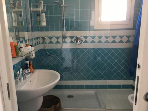bagno piastrellato blu con lavandino e doccia di Casa Moro a Trinità dʼAgultu