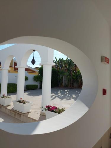 a view of a courtyard through a circular window at Hotel Villa Ionia in Avola
